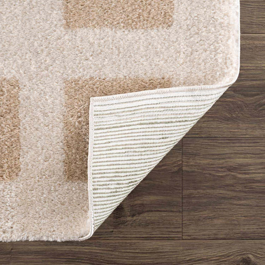 Close-up of the Beynon Beige Washable Area Rug showing its beige and peach geometric design and machine woven construction. Fold