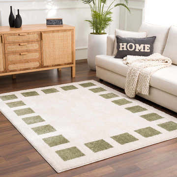 Living room scene with a Beynon Green Washable Area Rug, white sofa, wood cabinet, and potted plant. Roomscene-Rectangle