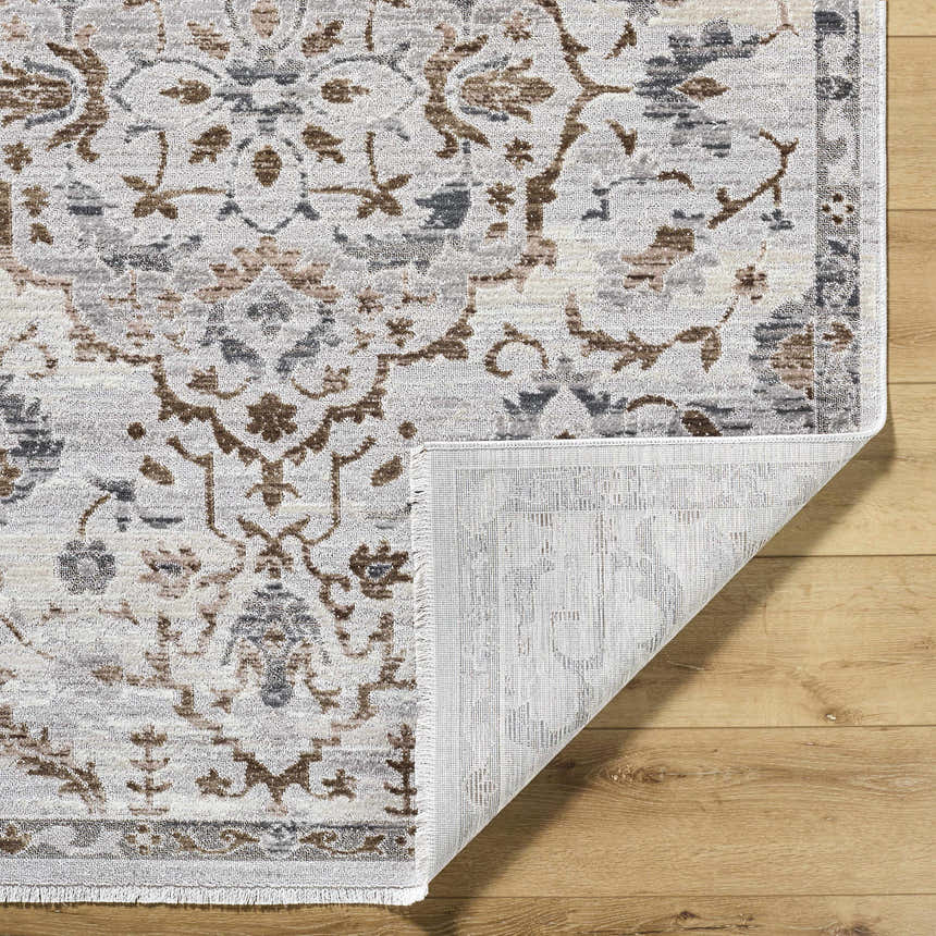 Close-up of the Aldona Area Rug showing its charcoal, ivory, slate gray, and taupe traditional pattern and soft polyester texture. Fold