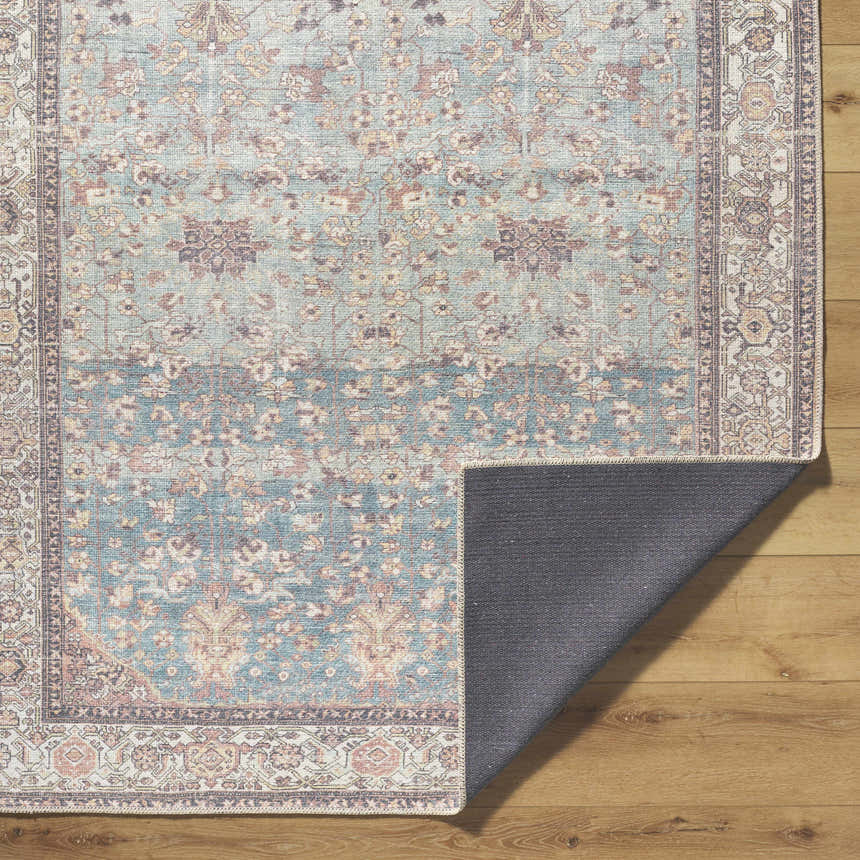Close-up of the Bahram Vintage Flat Pile Washable Rug. Features teal, cream, and dark red floral pattern. Machine woven polyester. Fold