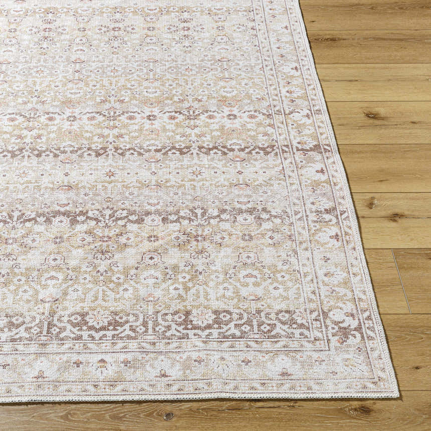 Close-up of Bienna Vintage Flat Pile Washable Rug. Farmhouse style rug in camel, cream, dark brown, peach, and tan on wood floor. Front