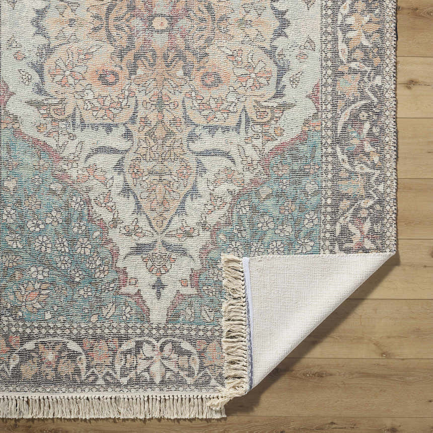 Close-up of the hand-loomed Bohdan Teal Area Rug showing its traditional design, teal, peach, and ivory colors, and cotton texture. Fold