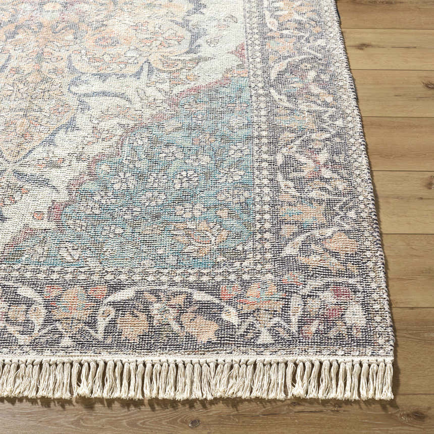 Close-up of the hand-loomed Bohdan Teal Area Rug showing its traditional design, fringe, and cotton texture on wood floors. Front