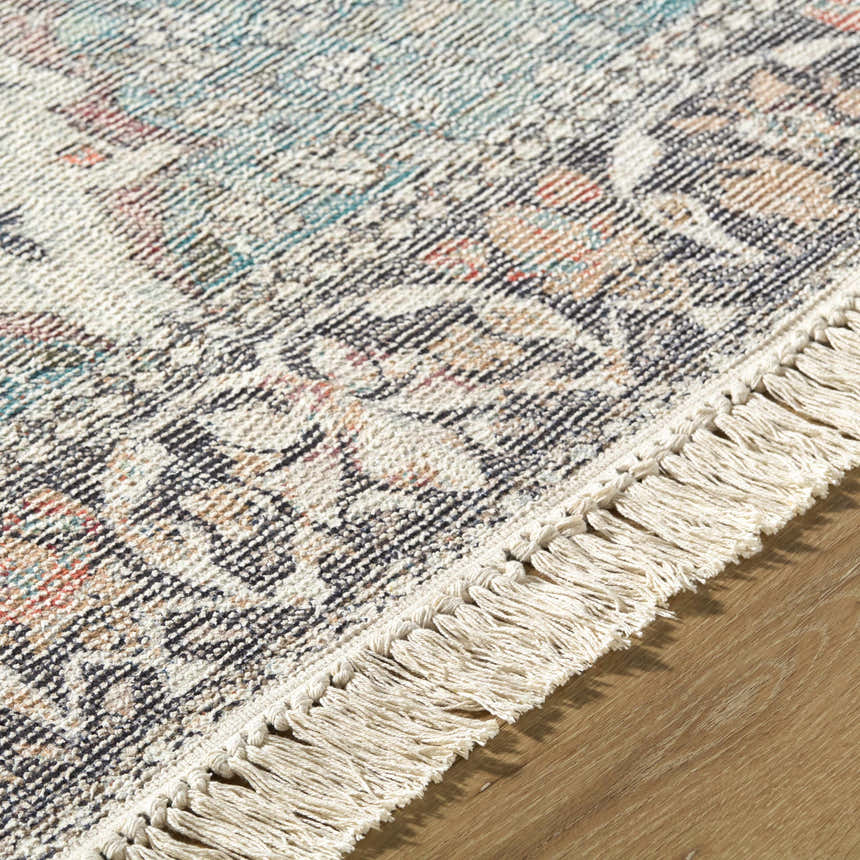 Close-up of the hand-loomed Bohdan Teal Area Rug showing its traditional pattern, fringe, and charcoal, teal, and ivory colors. Texture