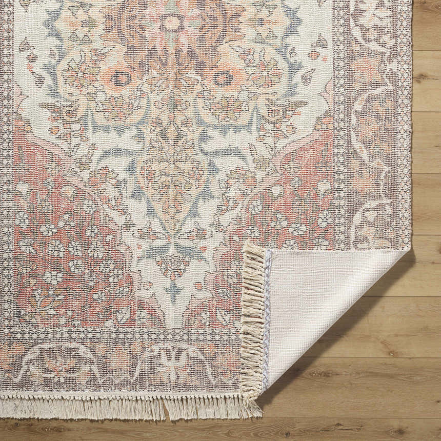 Close-up of the hand-loomed Bohdan Terracotta Area Rug showing the charcoal, ivory, and terracotta floral pattern and fringe. Fold