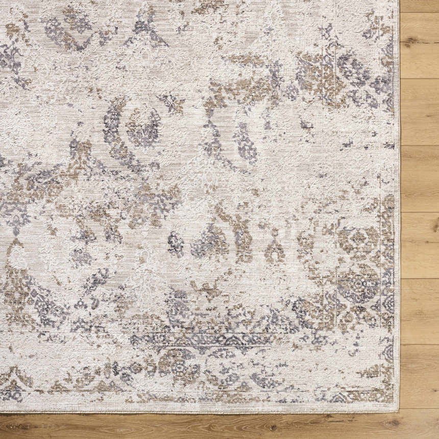 Close-up of the Breeda Charcoal Area Rug. Southwestern style rug in charcoal, cream, ivory, olive, and tan on a wood floor. Corner