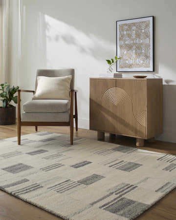 Living room scene with ash and desert sand Blaton Area Rug, gray chair, and wood cabinet. Roomscene-Rectangle