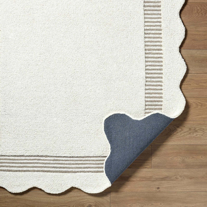 Close-up of the Tono Ivory Border Hand Tufted Wool Area Rug showing the texture, striped border, scalloped edge, and backing. Fold