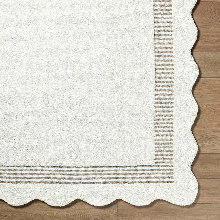Close-up of Tono Ivory Border Hand Tufted Wool Area Rug showing striped border, scalloped edge, and plush texture on wood floor. Corner
