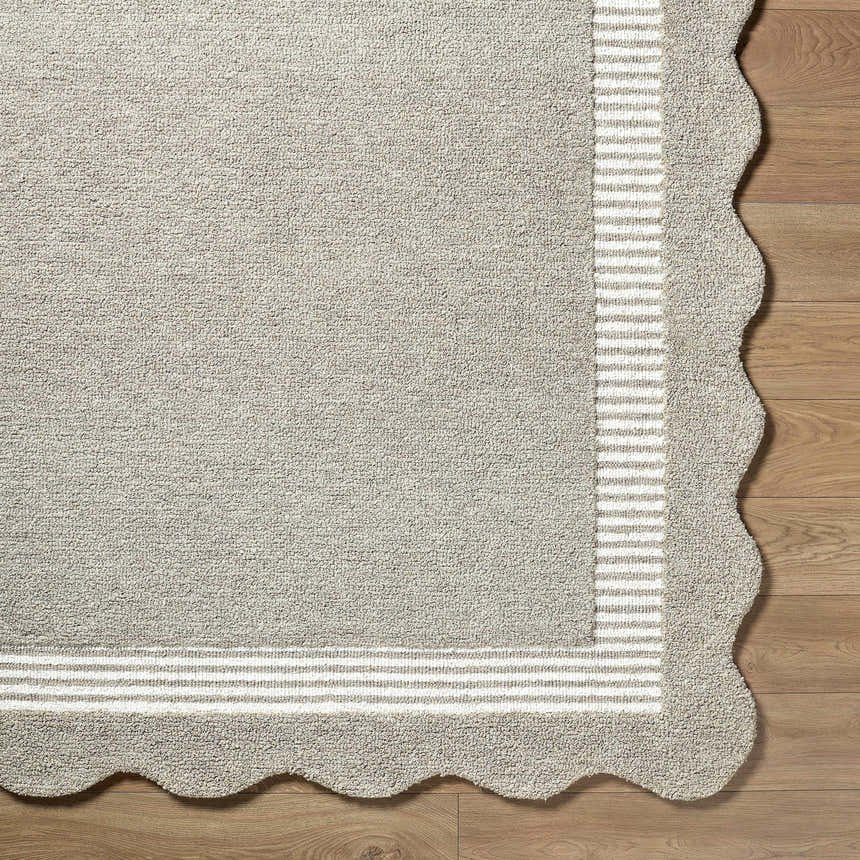 Close-up of the Fanae Beige Border Hand Tufted Wool Area Rug showing its texture, striped border, and scalloped edge. Corner