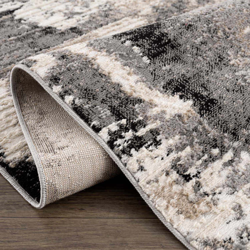 Close-up of the Birdie Area Rug. Ash, light silver, sage, and silver gray abstract pattern. Machine woven texture. Fold