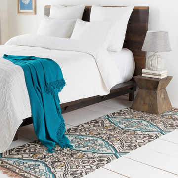 Bedroom scene with a Catherine Area Rug in blue, charcoal, brown, and mustard colors. Bohemian style on white wood floor. Roomscene-Runner