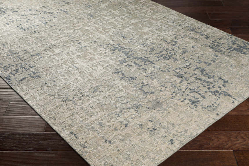 Close-up of Cayuga Area Rug in dark blue, sage, and off-white on dark wood floor. Contemporary silk rug texture. Corner