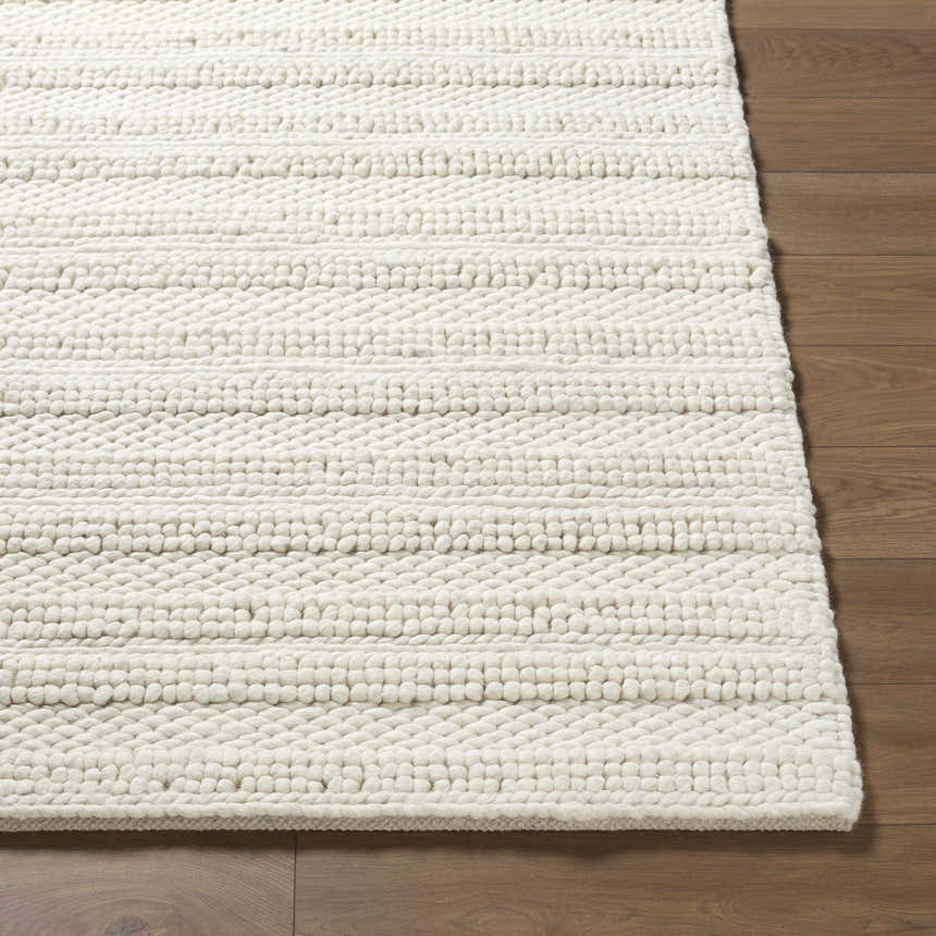 Close-up of the hand woven Coskun Area Rug showing its textured wool design and farmhouse style on wood floor. Front