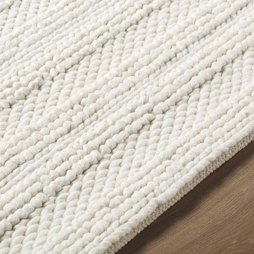 Close up of the hand woven Coskun Area Rug, showcasing its textured wool design and neutral color. Texture