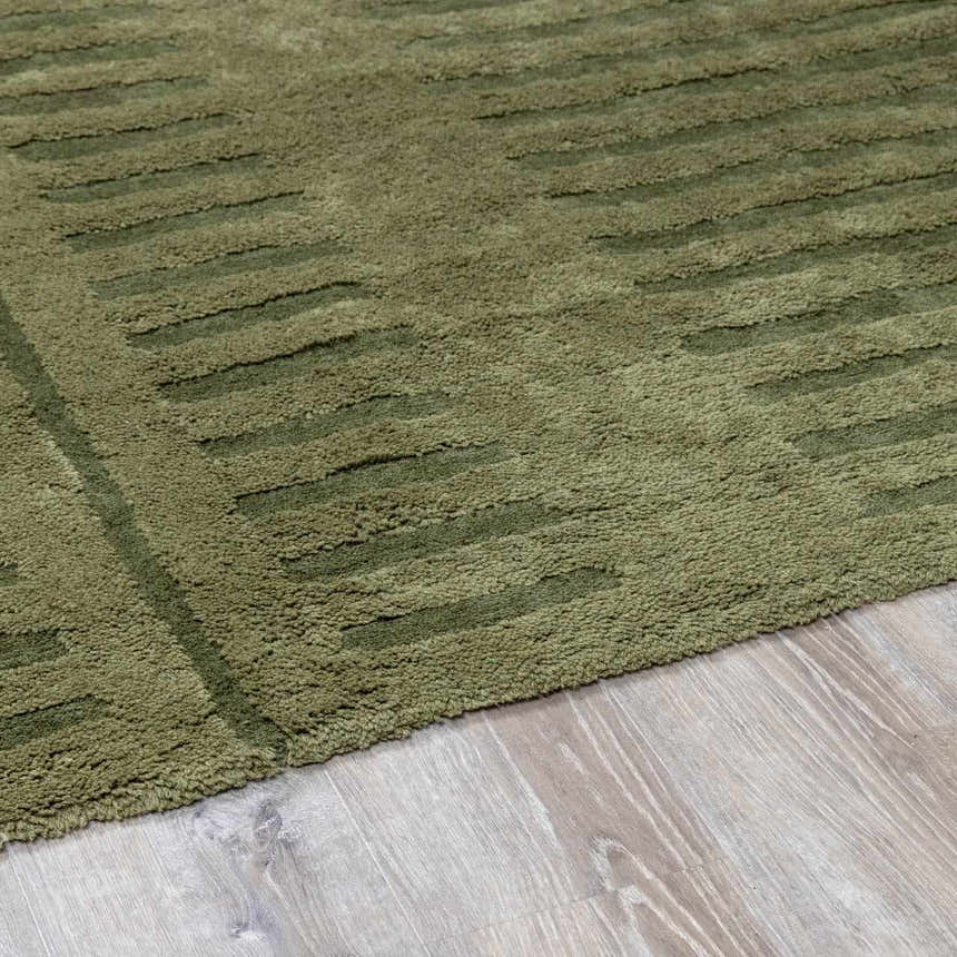 Close up of a green Washable Wool Rug with a textured, striped pattern on light wood flooring. Pile