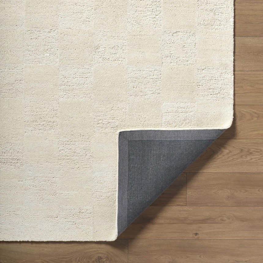 Close-up of the Chasya Ivory Area Rug showing its wool texture and grid pattern on hardwood floors. Fold