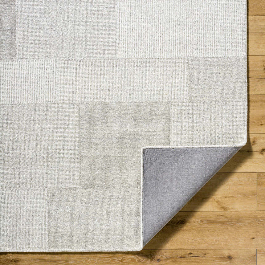 Close-up of the hand-tufted Camila Beige Area Rug showing its sandstone, taupe, and beige tones and wool texture. Fold
