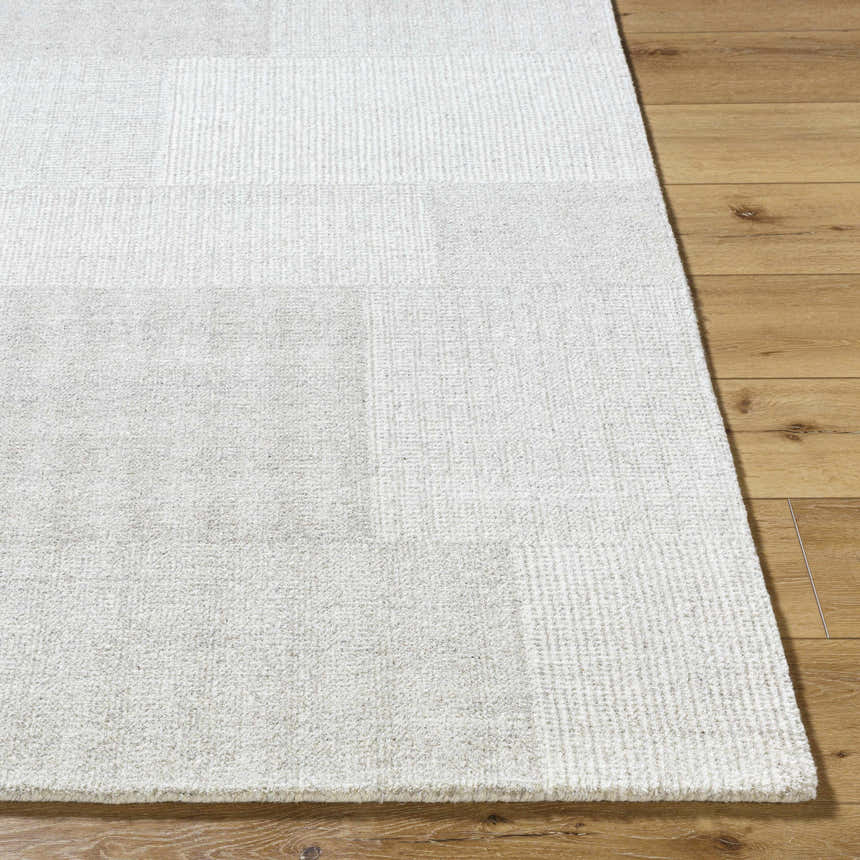 Close-up of the beige Camila Area Rug showing its subtle texture and pattern on a wood floor. Front