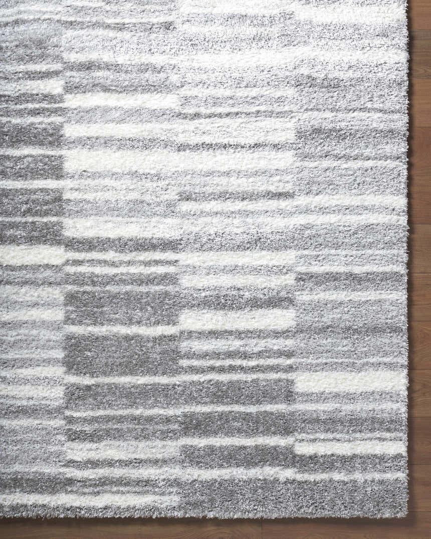 Close-up of the shag Carlen Gray Area Rug, featuring a contemporary gray, ivory, and light gray striped pattern. Corner