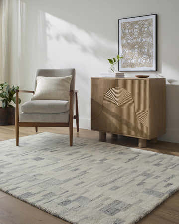 Living room scene with Becki Owens x LIVABLISS BOMX-2303 rug in blue, gray, and ivory, styled with a chair and cabinet. Roomscene-Rectangle