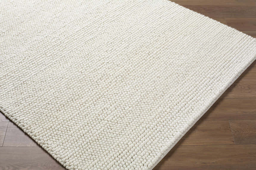 Close-up of the beige Clayne rug. The premium wool rug has a soft, nubby texture. Corner