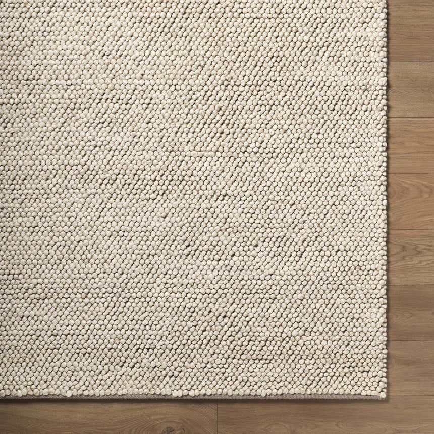 Close up of the hand woven Clayne Dark Beige wool rug showing its looped texture and medium brown color. Corner