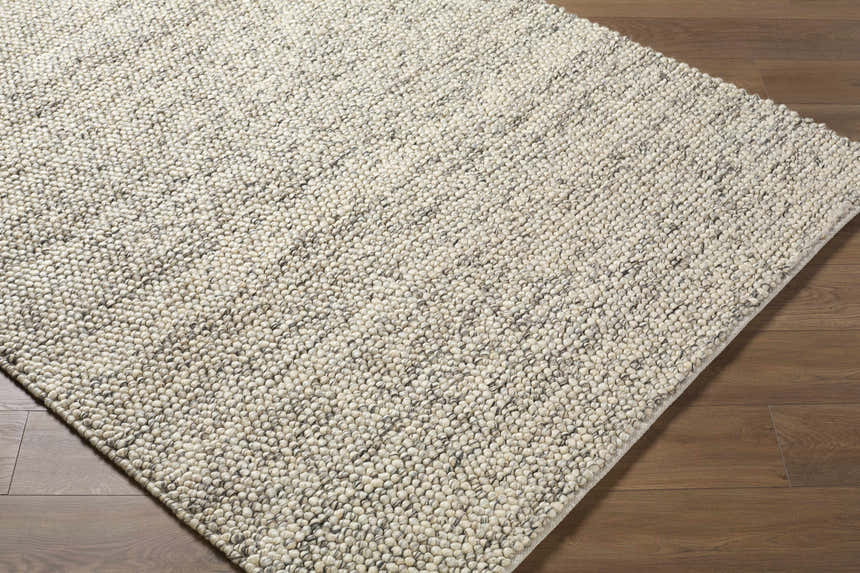 Close-up of the hand woven Clayne Beige & Charcoal Premium Wool Area Rug, showing its textured, looped wool design. Corner