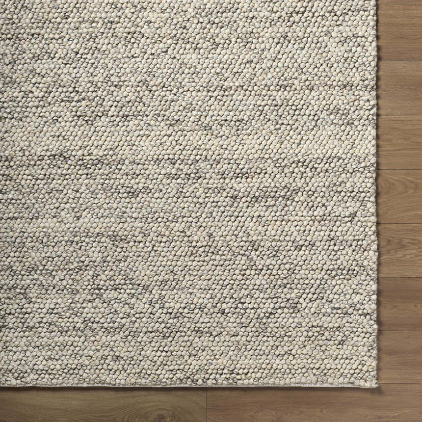 Close-up of the hand woven Clayne Beige & Charcoal Premium Wool Area Rug showing its textured, looped wool design. Corner