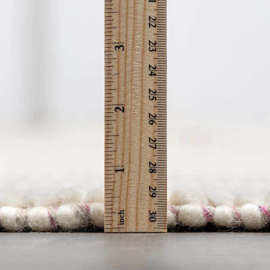 Close-up of the Ramsbury Soft Pink Wool Rug showing its pile height with a ruler. Pink accents. Pile