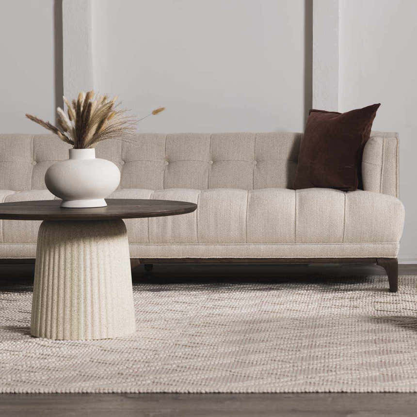 Living room scene with a Ramsbury Soft Pink Wool Rug, beige sofa, and round coffee table. Roomscene-Rectangle