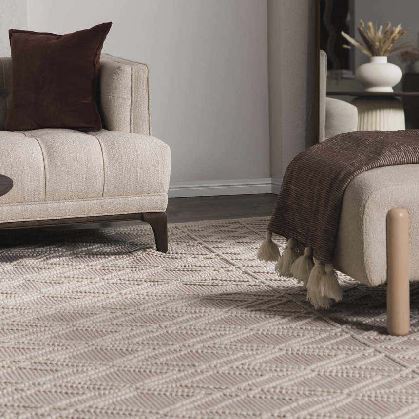 Living room scene with a Ramsbury Soft Pink Wool Rug, beige sofa, brown throw, and geometric pattern. Roomscene-Rectangle
