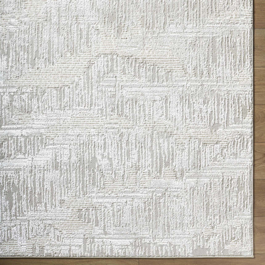 Close-up of the Annisa Area Rug, showcasing its cream, ivory, and light gray contemporary geometric design and textured weave. Corner
