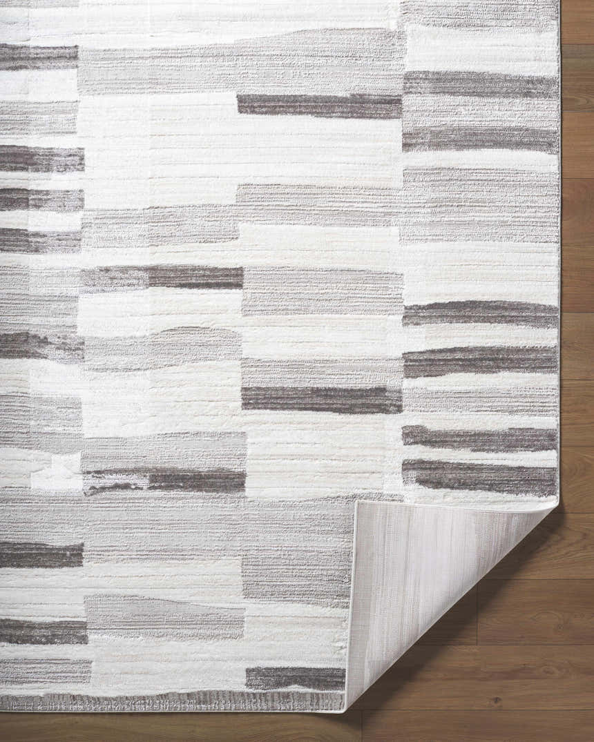 Close up of the Ananya Area Rug. Contemporary design in ivory, light brown, medium gray, peach, and taupe. Fold