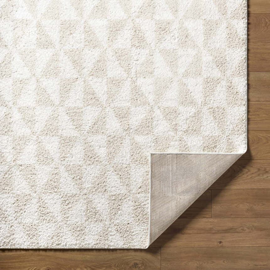 Close-up of the Ceylan Area Rug. Medium gray and white shag rug with geometric pattern. Machine woven polyester rug. Fold