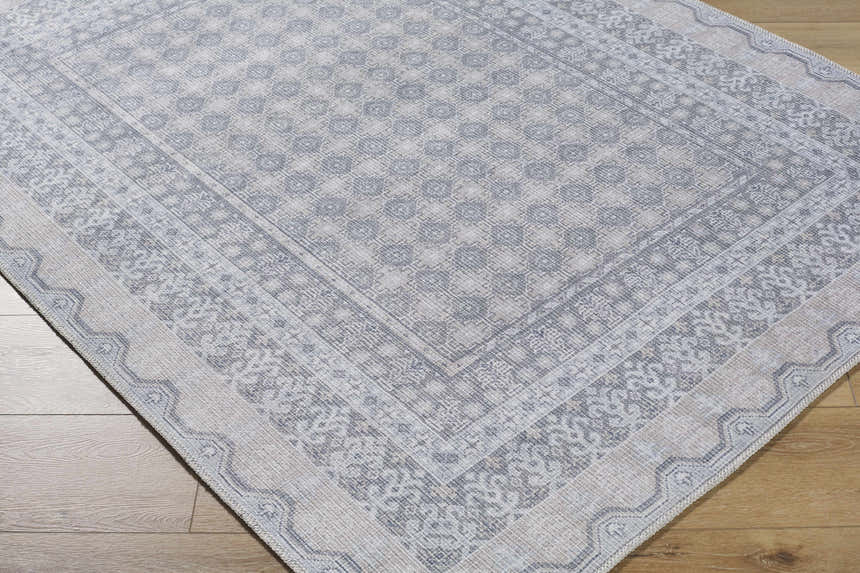Close-up of the Rainier Blue Washable Rug showing its traditional, pale blue and white pattern and soft texture. Corner