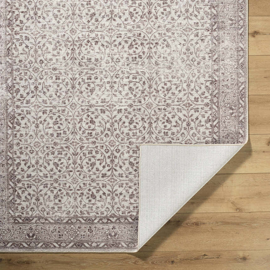 Close-up of the Spokane Brown Area Rug. Farmhouse style rug with burnt orange and cream floral pattern on a tan background. Fold