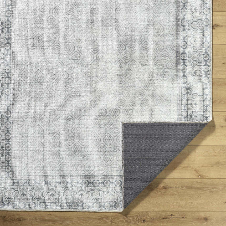 Close-up of the Rainier Cottage Border Gray Washable Rug showing its farmhouse design and gray, off-white color palette. Fold