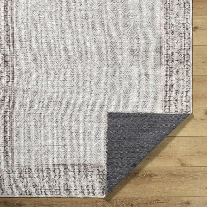 Close-up of Rainier Cottage Border Beige Washable Rug showing traditional pattern, charcoal border, and non-slip backing. Fold