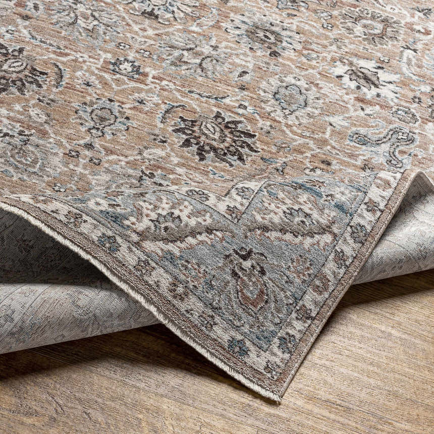 Close-up of the Civankan Area Rug. Traditional oriental pattern in brick red, denim, dusty sage, and brown on a wood floor. Fold
