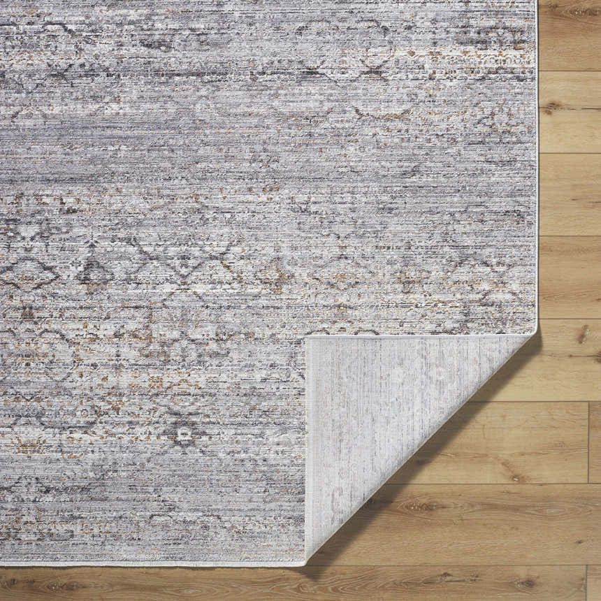 Close-up of the Cemile Area Rug showing its black, gray, ivory, and taupe traditional pattern and texture on wood floor. Fold