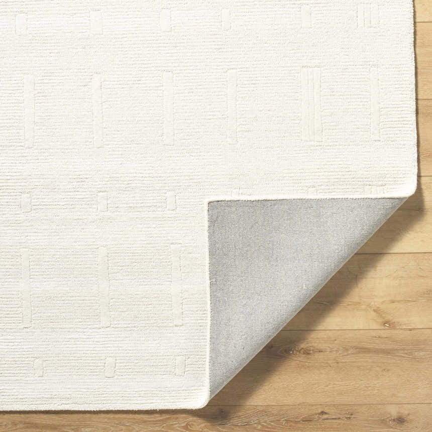 Close-up of the hand-tufted Charan Ivory Cream Area Rug showing its geometric design, wool texture, and backing. Fold