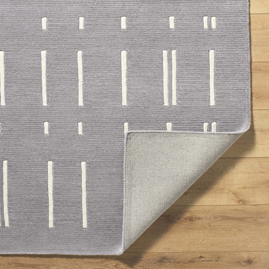 Close up of the Charan Slate Gray Area Rug showing ivory stripes and hand tufted wool texture. Fold