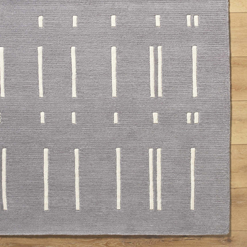 Close up of the Charan Slate Gray Area Rug. Gray wool rug with ivory vertical stripe pattern. Contemporary style. Corner