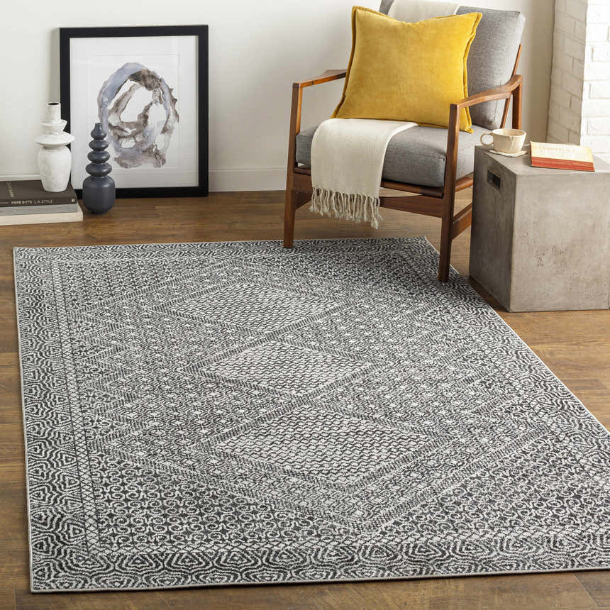 Living room scene with Coledale Black & White Washable Rug, gray chair, yellow pillow, and modern decor. Roomscene-Rectangle