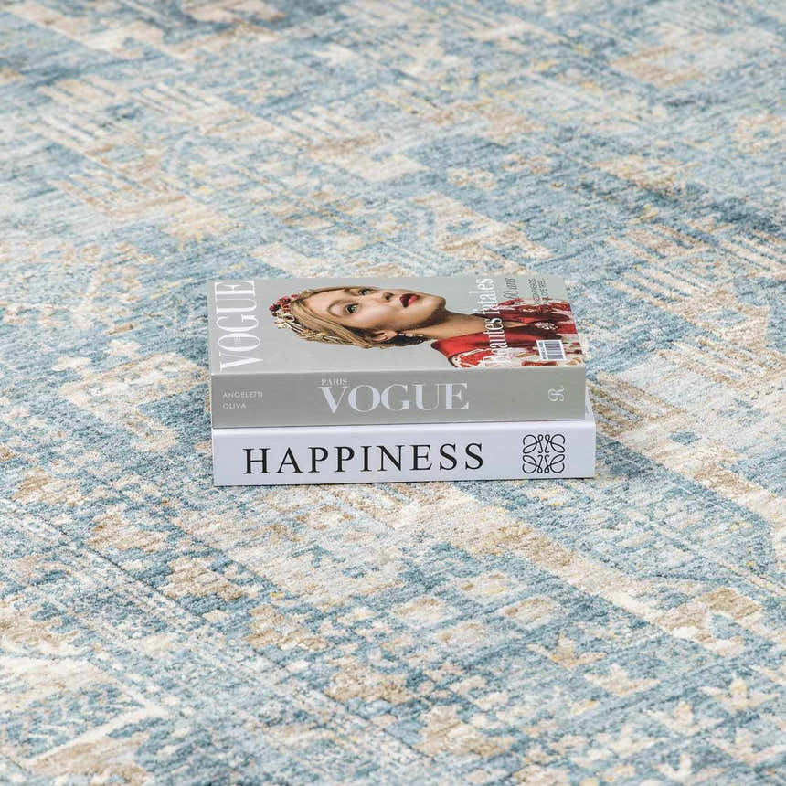 Close-up of the Mirabel Denim Blue Traditional Rug with a stack of fashion books on top. Styleshot
