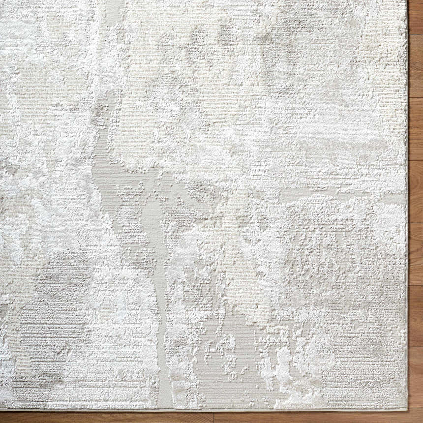 Close-up of the textured Chroma Abstract Cream Area Rug with ivory, light gray, and white tones on wood flooring. Corner
