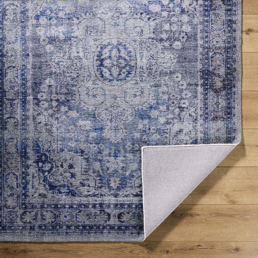 Close-up of the hand-tufted Csilla Area Rug. Traditional design in arctic sky, blue, ivory, and slate blue on wood floors. Fold