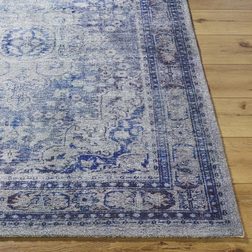 Close-up of the Csilla Area Rug. Hand-tufted polyester rug in arctic sky, blue, ivory, and slate blue on a wood floor. Front