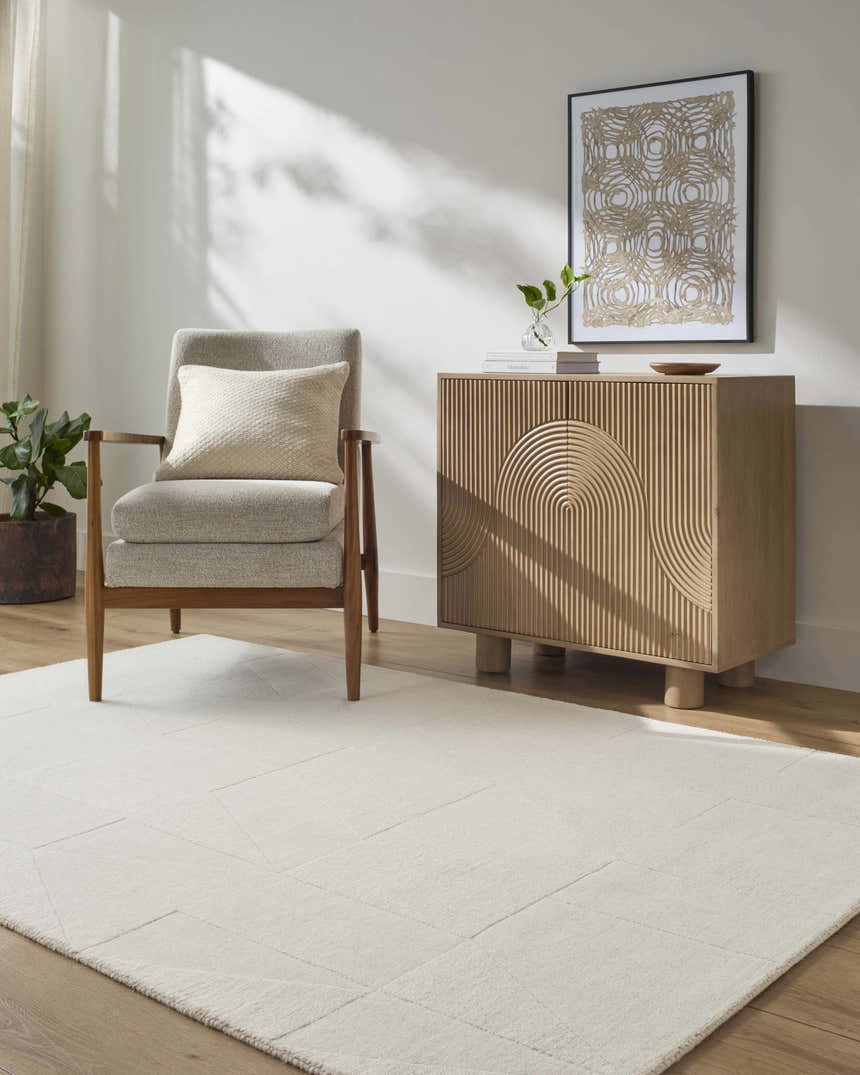 Living room scene with ivory Callie Area Rug, gray armchair, and wood cabinet. Modern, neutral tones. Roomscene-Rectangle